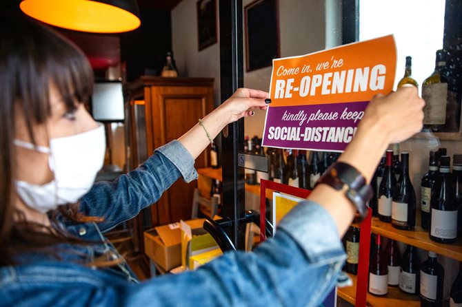Business owner with mask hanging sign